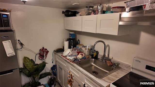 kitchen with white cabinets, stainless steel appliances, light countertops, and a sink