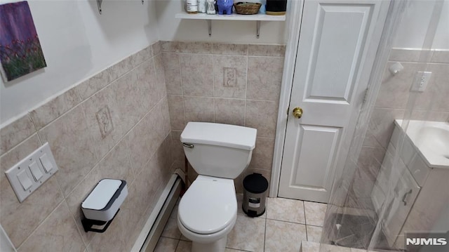 bathroom with a baseboard heating unit, tile patterned floors, toilet, tile walls, and wainscoting