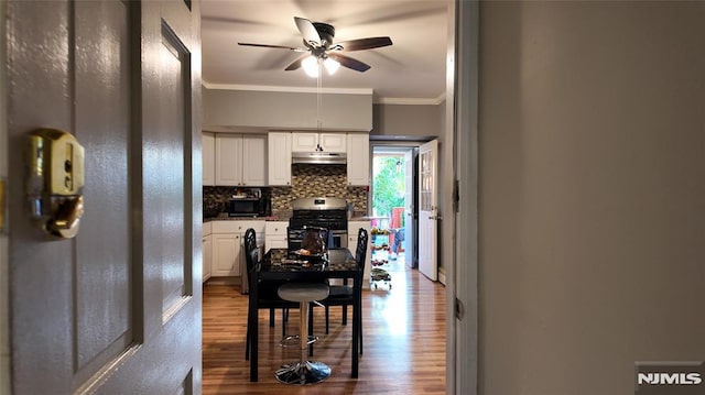 dining space with ceiling fan, crown molding, and dark wood-type flooring