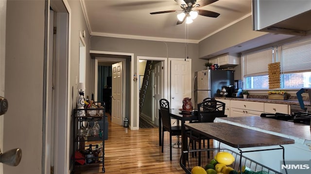 kitchen with a ceiling fan, crown molding, dark countertops, light wood-style flooring, and white cabinets