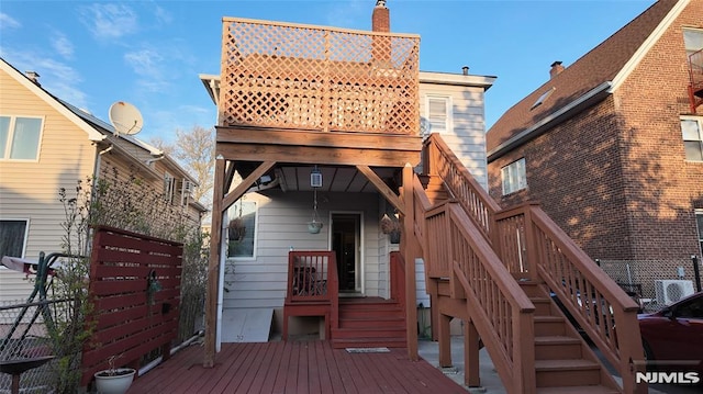 rear view of property with fence, a wooden deck, and stairs