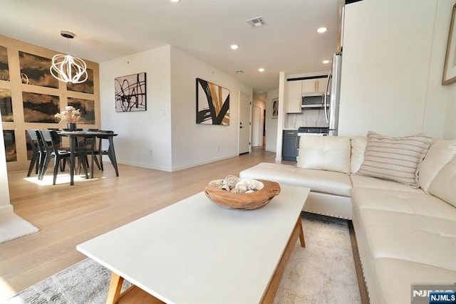 living area with recessed lighting, an inviting chandelier, visible vents, light wood-style floors, and baseboards