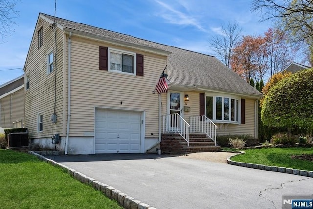 split level home featuring a garage, central air condition unit, driveway, and a front yard