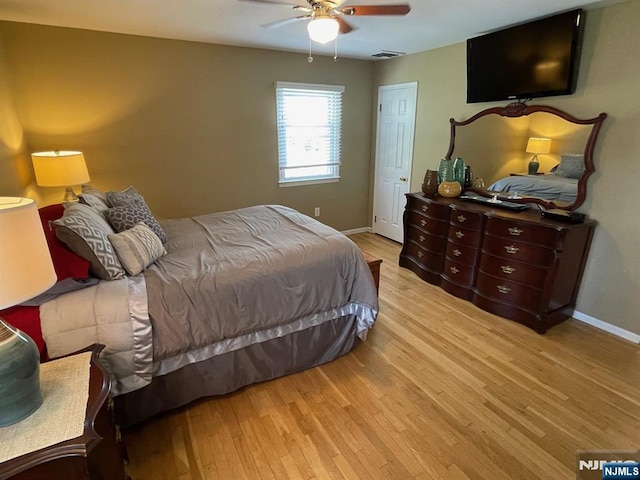 bedroom featuring light wood-type flooring, baseboards, ceiling fan, and visible vents