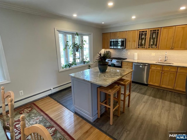 kitchen featuring dark wood-style floors, baseboard heating, a center island, a sink, and stainless steel appliances