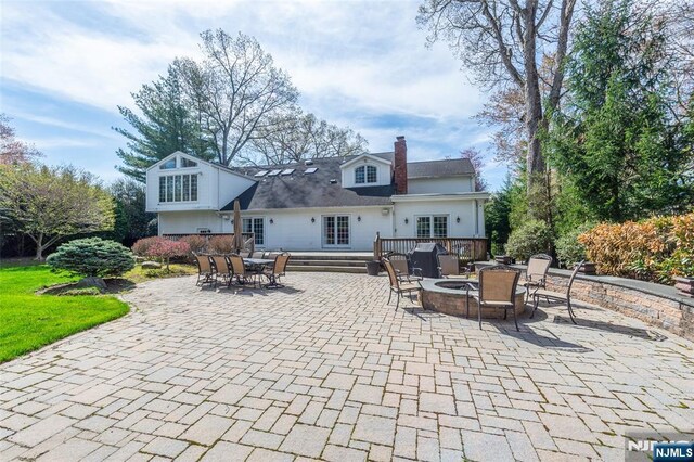 38 Farley Pl, Allendale, NJ 07401 - rear view of property featuring a chimney, outdoor dining space, a fire pit, a patio, and a wooden deck