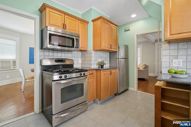 kitchen featuring appliances with stainless steel finishes, dark stone counters, decorative backsplash, and baseboards