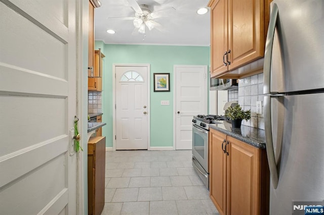 kitchen with tasteful backsplash, stainless steel appliances, brown cabinets, baseboards, and a ceiling fan