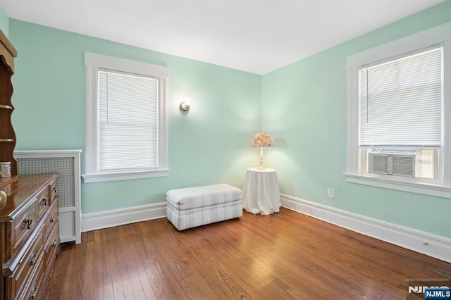 sitting room with hardwood / wood-style floors, cooling unit, and baseboards