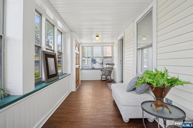 sunroom / solarium featuring a wainscoted wall, wood finished floors, and plenty of natural light