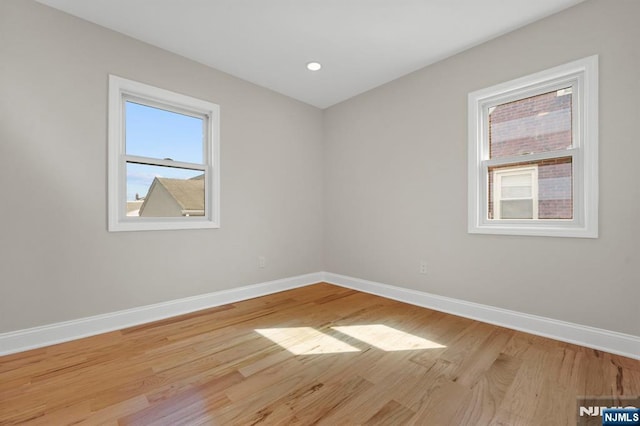 spare room featuring recessed lighting, wood finished floors, and baseboards