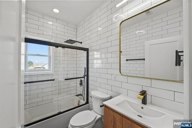 bathroom featuring shower / bath combination with glass door, tile walls, vanity, decorative backsplash, and toilet