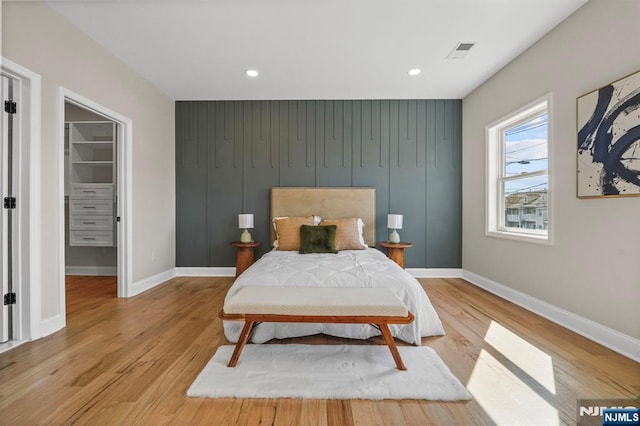 bedroom featuring visible vents, a spacious closet, light wood-style flooring, and baseboards