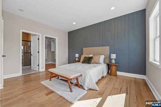 bedroom with baseboards, light wood-style flooring, and a spacious closet