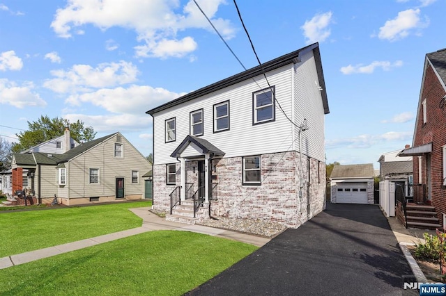 view of front of property featuring driveway, an outdoor structure, a front lawn, brick siding, and a garage
