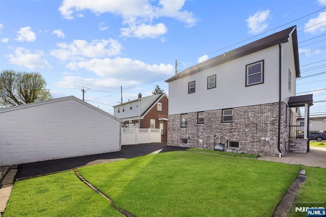 back of house with a lawn, brick siding, and fence