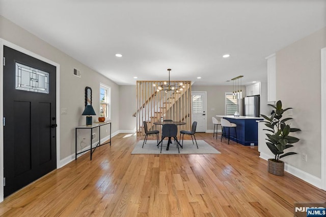 entrance foyer with baseboards, an inviting chandelier, and light wood finished floors