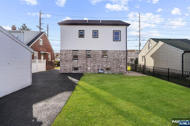 back of house featuring fence and a lawn