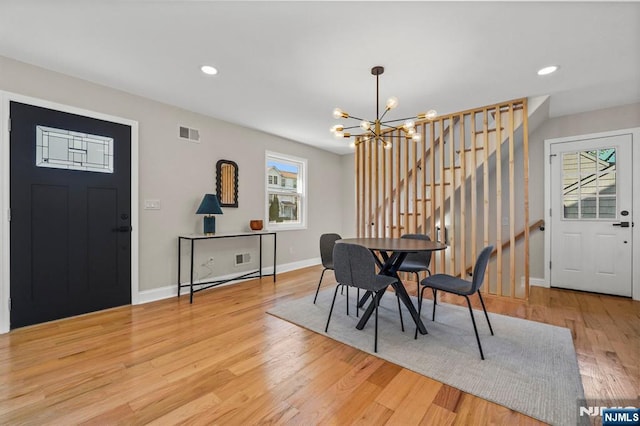 dining room with stairway, visible vents, a chandelier, light wood-style floors, and baseboards