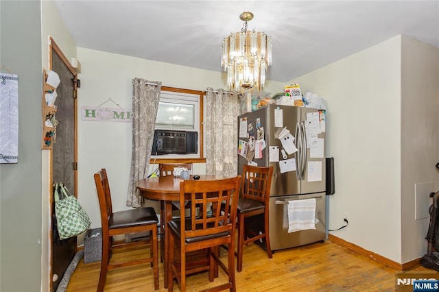 dining space featuring baseboards, wood finished floors, a chandelier, and cooling unit