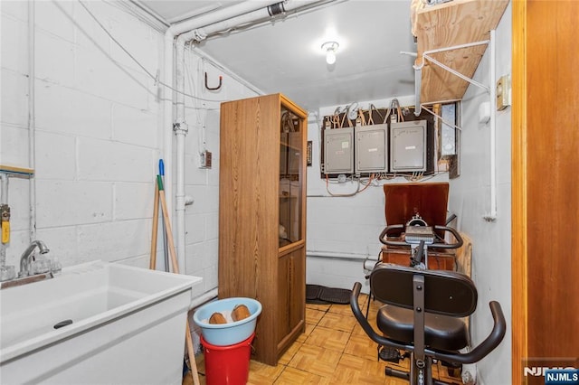 interior space with concrete block wall, a sink, and electric panel