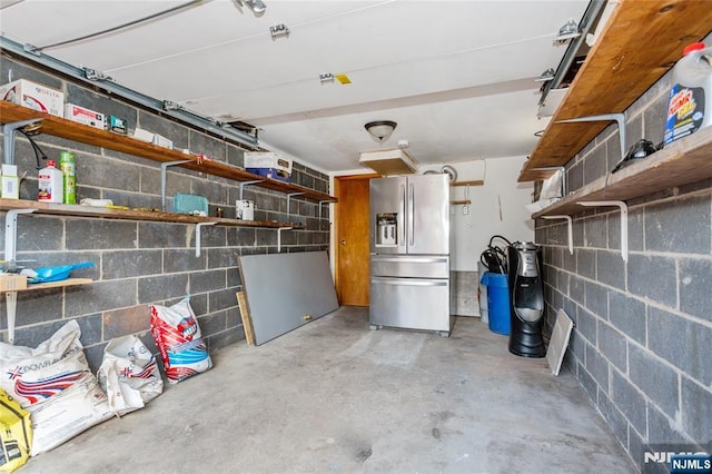 garage with concrete block wall and stainless steel fridge with ice dispenser