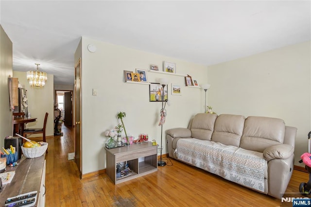 living room featuring baseboards, a chandelier, and hardwood / wood-style flooring