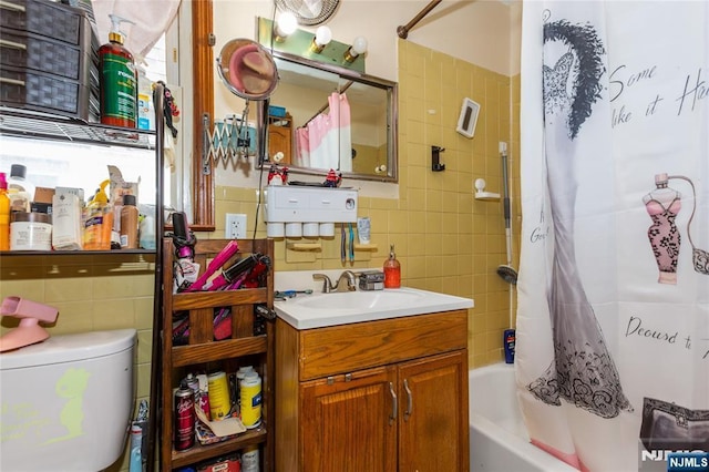 bathroom with tile walls, vanity, toilet, and shower / tub combo
