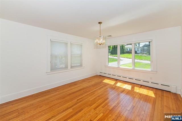 empty room featuring baseboards, a chandelier, light wood finished floors, and a baseboard radiator