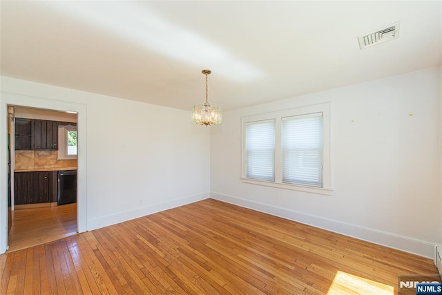 unfurnished room featuring baseboards, a chandelier, light wood-style flooring, and visible vents