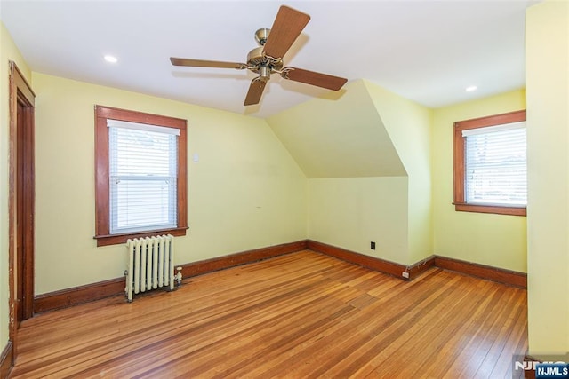 bonus room featuring baseboards, a healthy amount of sunlight, light wood-style flooring, and radiator
