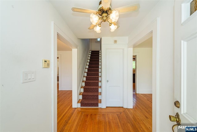 stairs with baseboards, ceiling fan, and wood finished floors