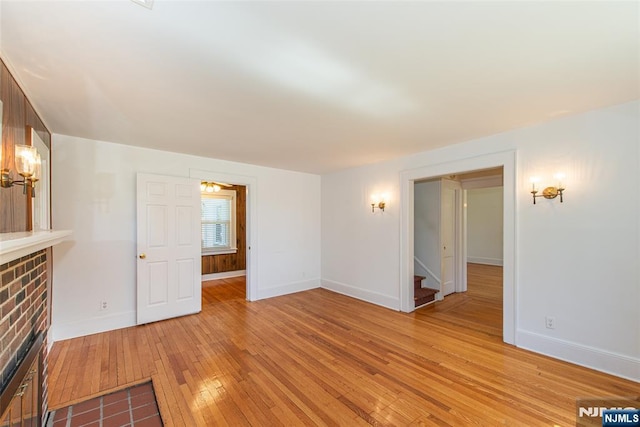 unfurnished living room with stairway, baseboards, and light wood finished floors