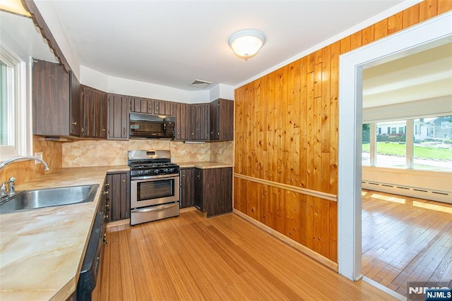 kitchen featuring stainless steel gas range, dark brown cabinetry, black microwave, and a sink