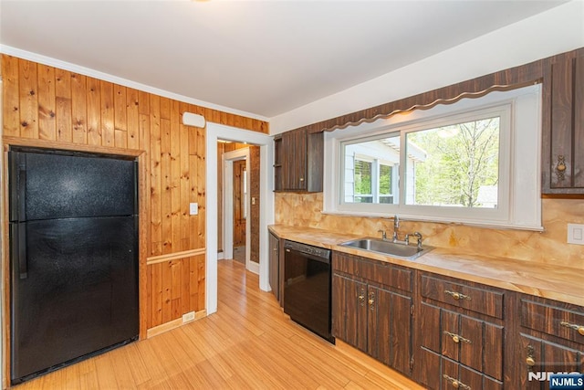 kitchen featuring a sink, decorative backsplash, black appliances, and light wood-type flooring