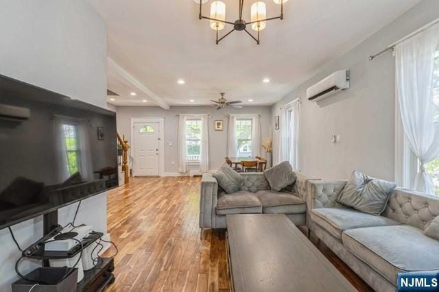 living area featuring recessed lighting, an inviting chandelier, light wood finished floors, and an AC wall unit