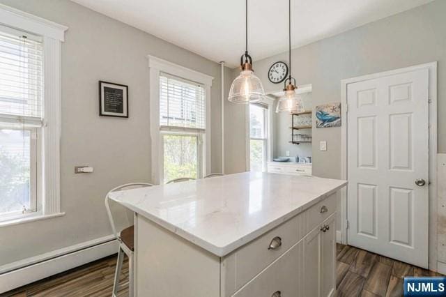 kitchen featuring a baseboard heating unit, dark wood-style flooring, a center island, light countertops, and white cabinets
