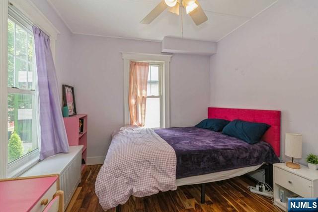 bedroom featuring wood finished floors, ceiling fan, and multiple windows