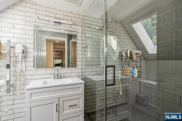 bathroom with vanity, a shower stall, visible vents, and tile walls