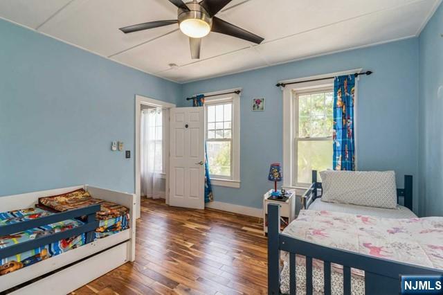 bedroom featuring baseboards, wood finished floors, and a ceiling fan