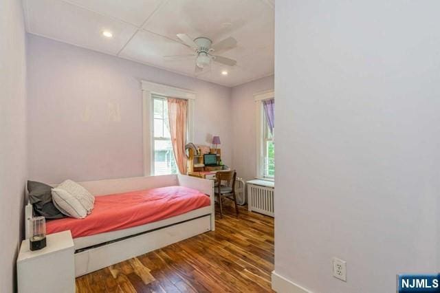 bedroom with baseboards, radiator heating unit, wood finished floors, and recessed lighting