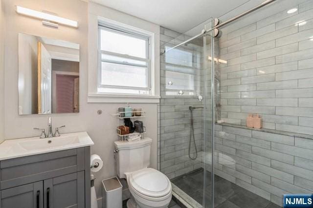 full bathroom with a stall shower, toilet, and vanity