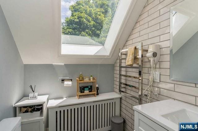 interior space featuring radiator, lofted ceiling, and decorative backsplash