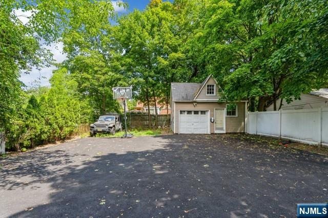garage featuring fence and aphalt driveway