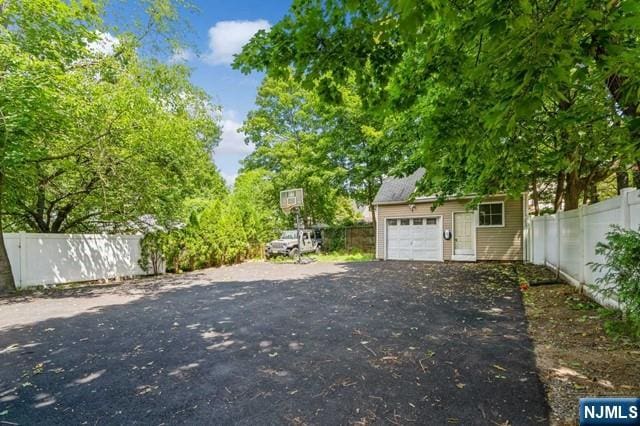 exterior space with fence, an outdoor structure, aphalt driveway, and a garage