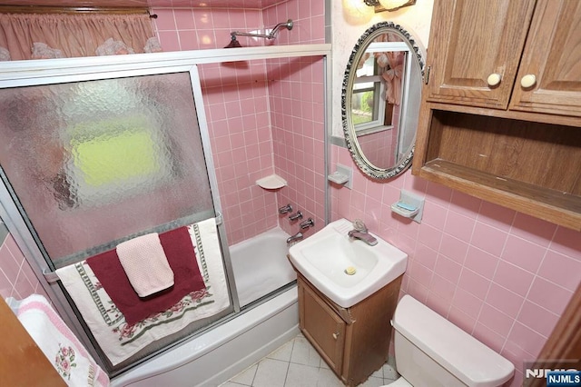 bathroom featuring bath / shower combo with glass door, toilet, tile walls, tile patterned floors, and vanity
