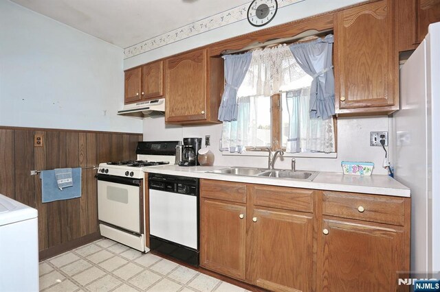 kitchen with white appliances, under cabinet range hood, light countertops, a sink, and washer / clothes dryer