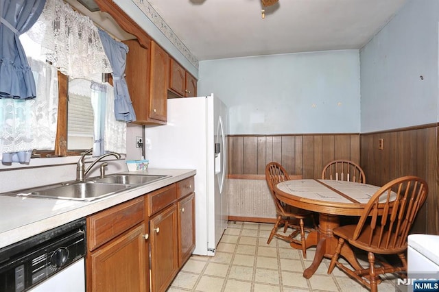kitchen featuring light floors, white appliances, wainscoting, and a sink