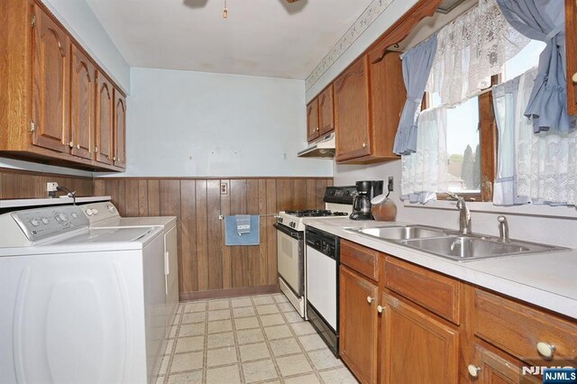 kitchen with a sink, washing machine and dryer, white range with gas cooktop, under cabinet range hood, and light floors