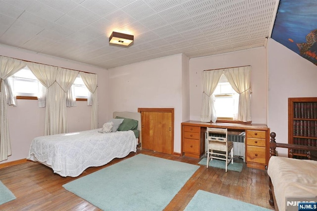 bedroom featuring radiator heating unit and hardwood / wood-style flooring